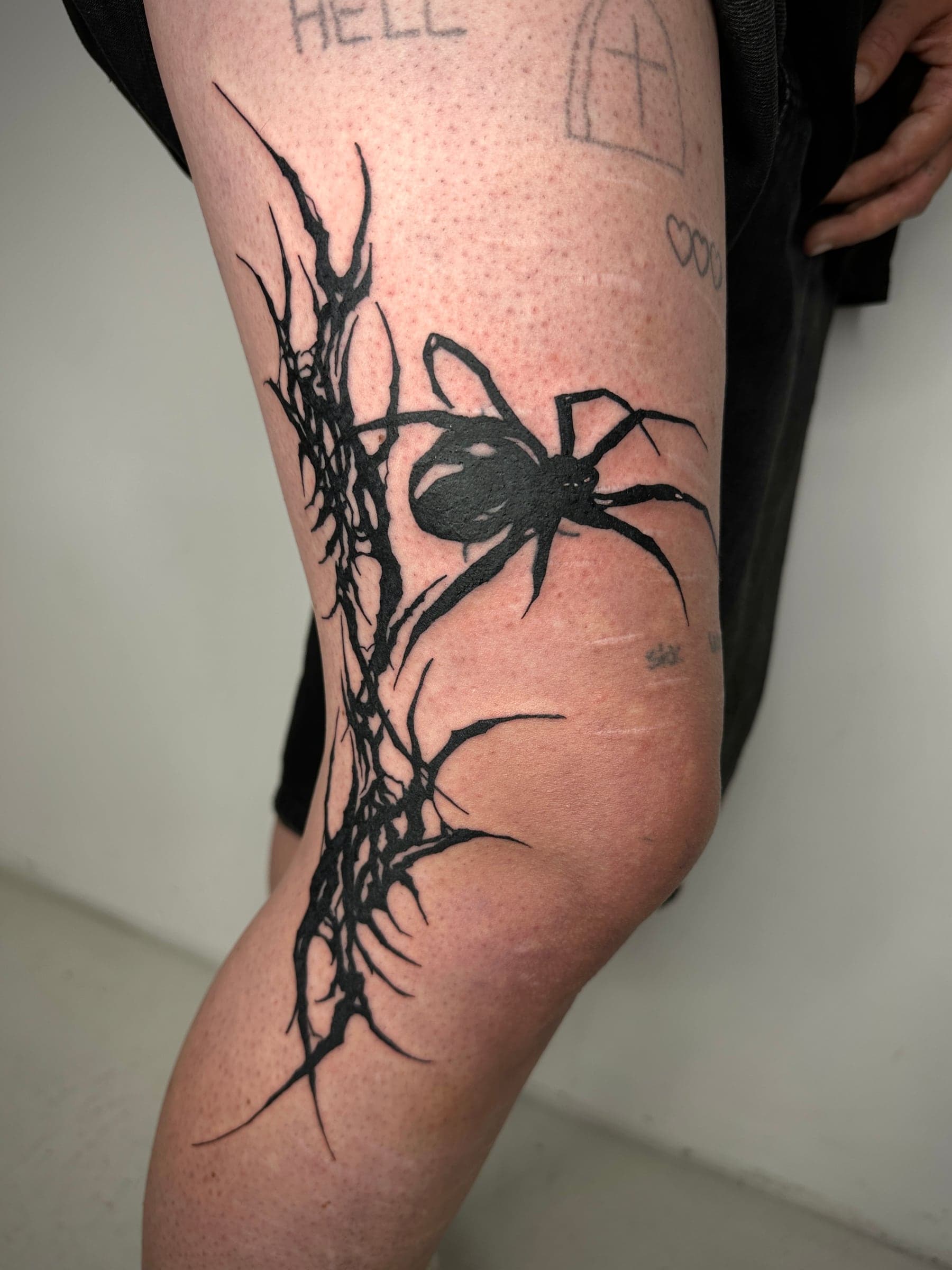 Blackwork-Tattoo einer Schwarzen Witwe auf einem dornigen Ast, Bein