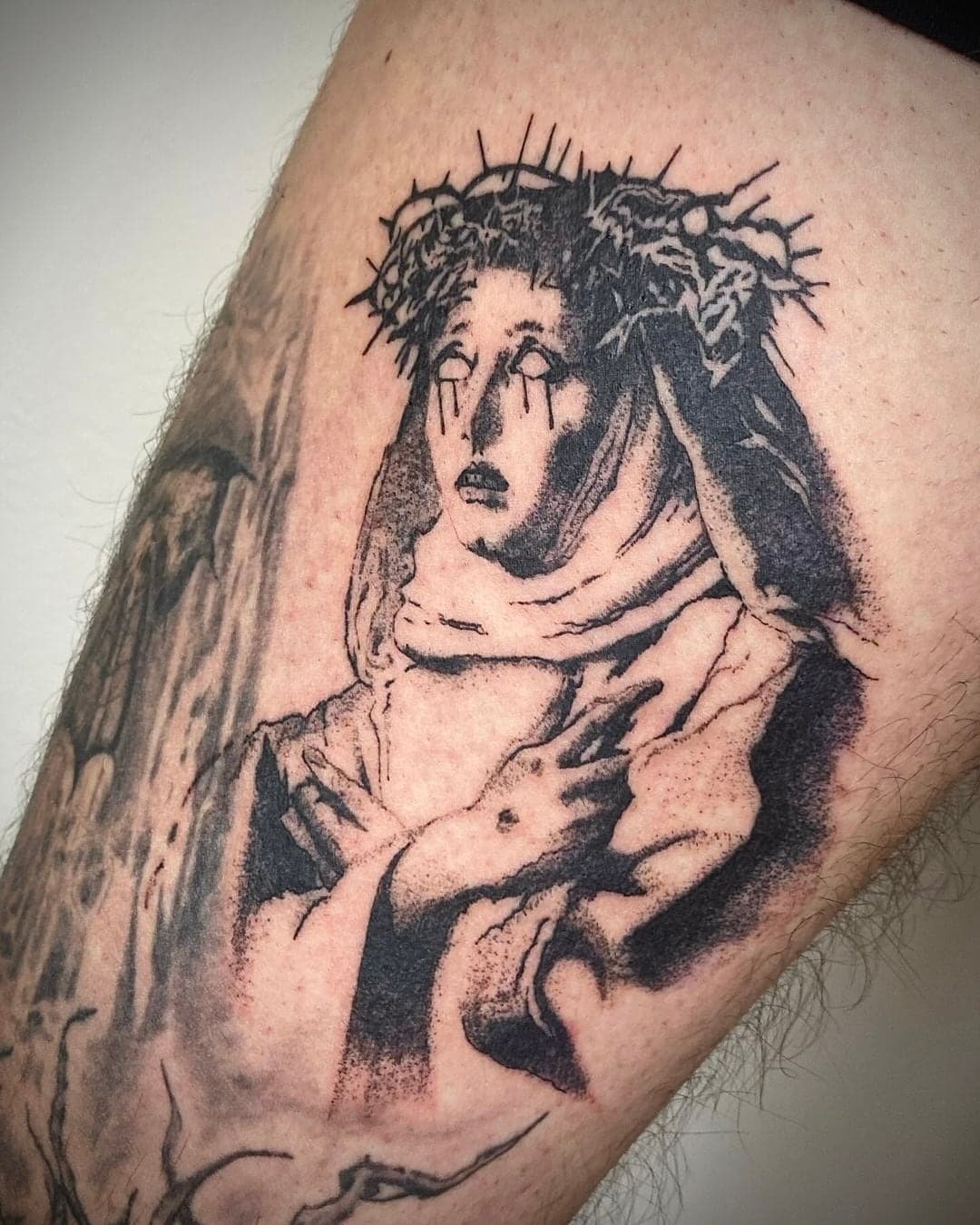 Feines Linework-Tattoo einer trauernden Figur mit Dornenkrone, Oberarm